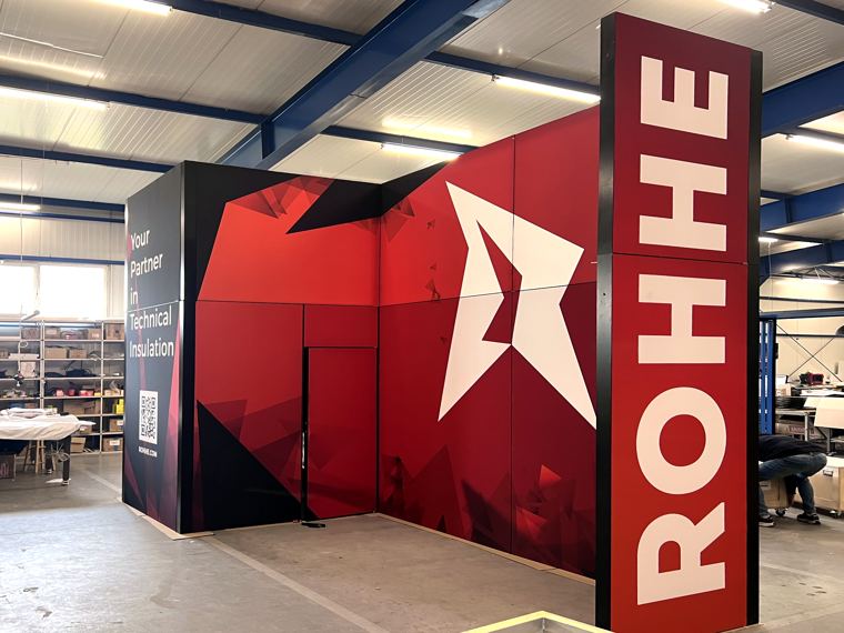 Narożnik stoiska ROHHE z czerwoną grafiką, hala produkcyjna