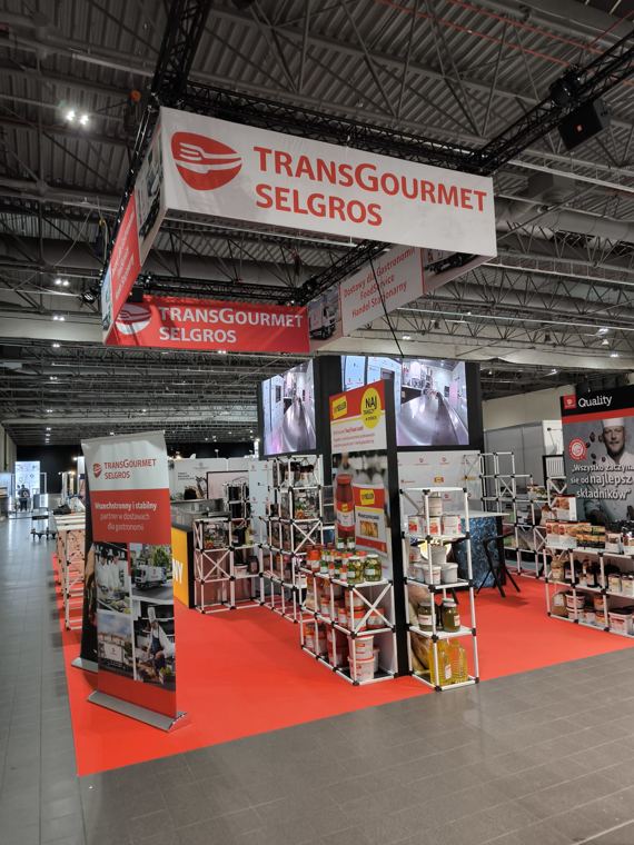 Stoisko Transgourmet Selgros z regałami produktowymi na podeście