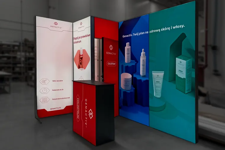 Stoisko Genactiv z drugim kompletem tkanin: czerwona grafika na lewej ścianie, drzwiach kantorka i ladzie, niebiesko-turkusowa ściana z produktami bez zmian