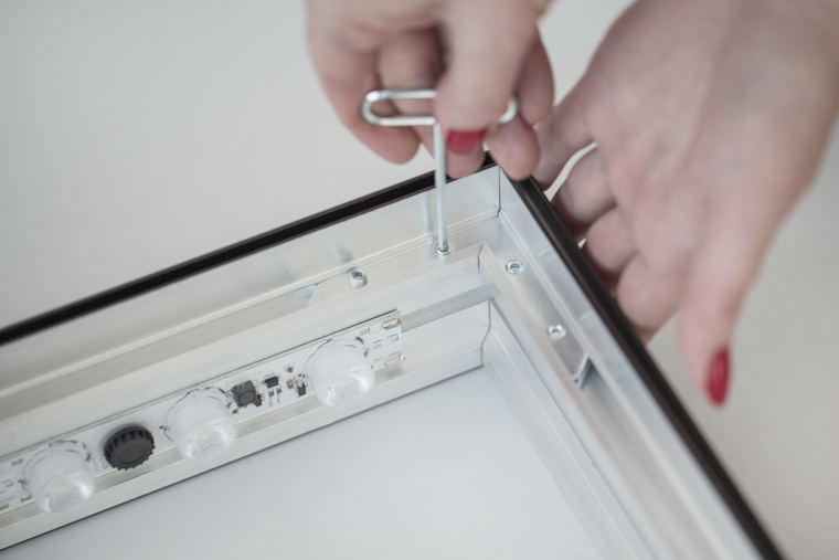 Skręcanie ramy M100 LED kluczem imbusowym, widoczne moduły LED w profilu
