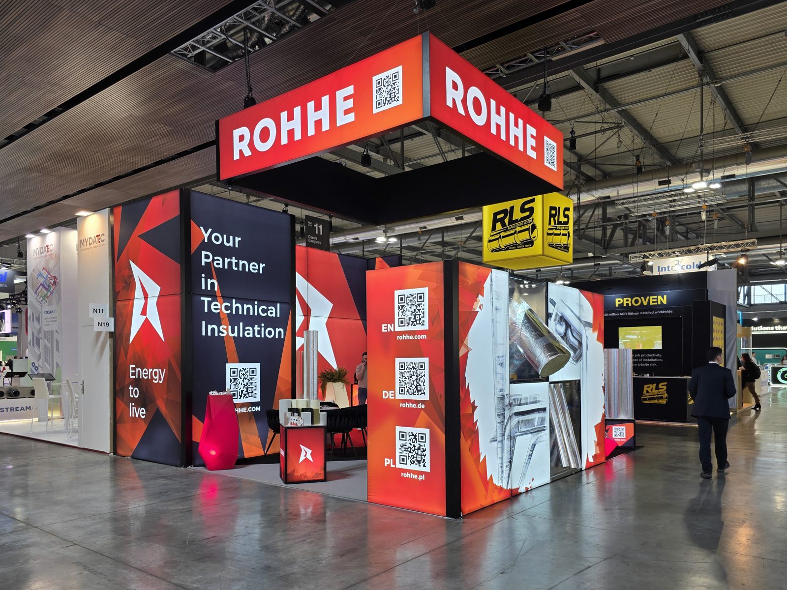 Stoisko ROHHE w hali targowej: podwieszany szyld ROHHE, ściany LED z hasłem Your partner in technical insulation